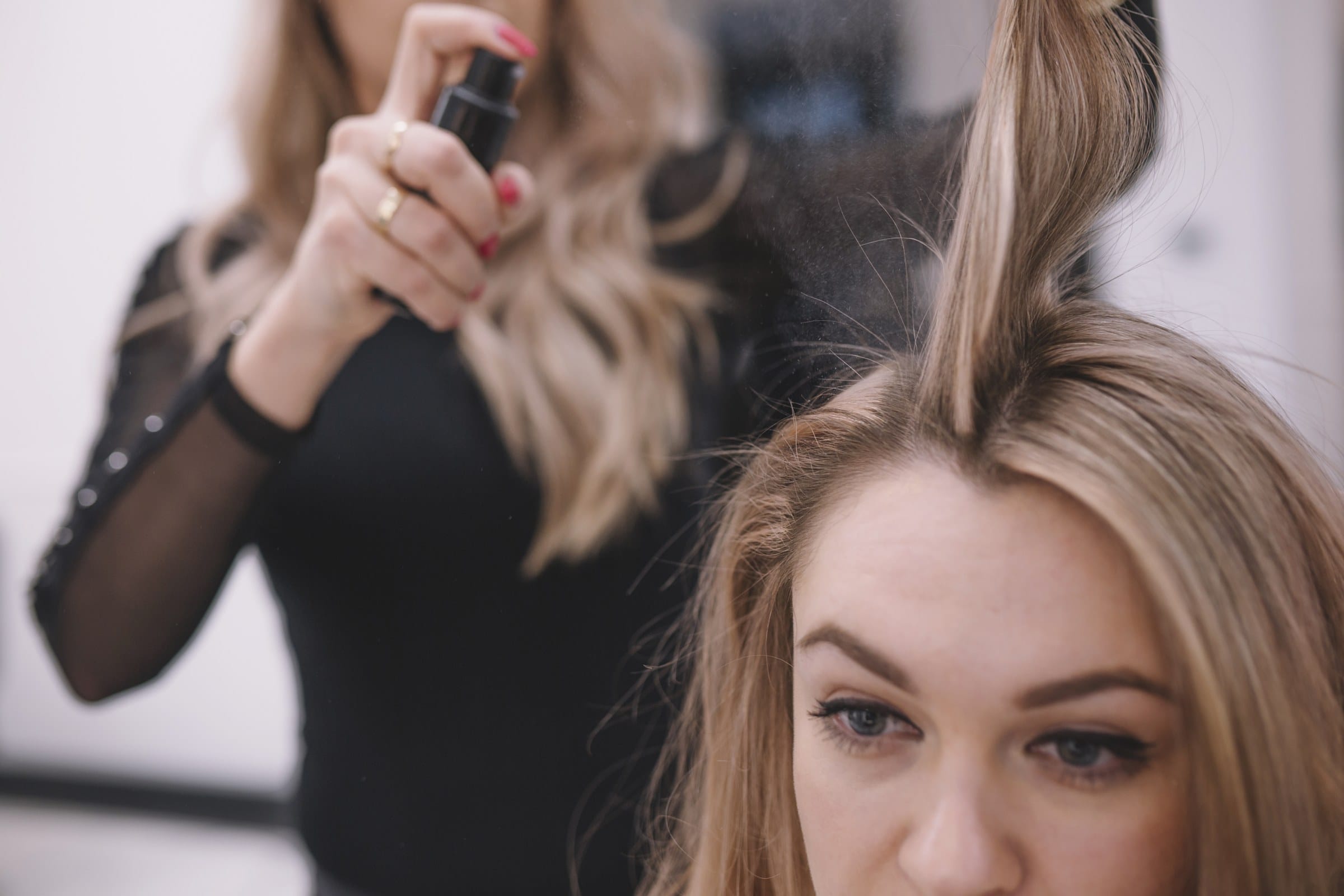 Fryzjer aplikuje spray zwiększający objętość cienkich włosów
